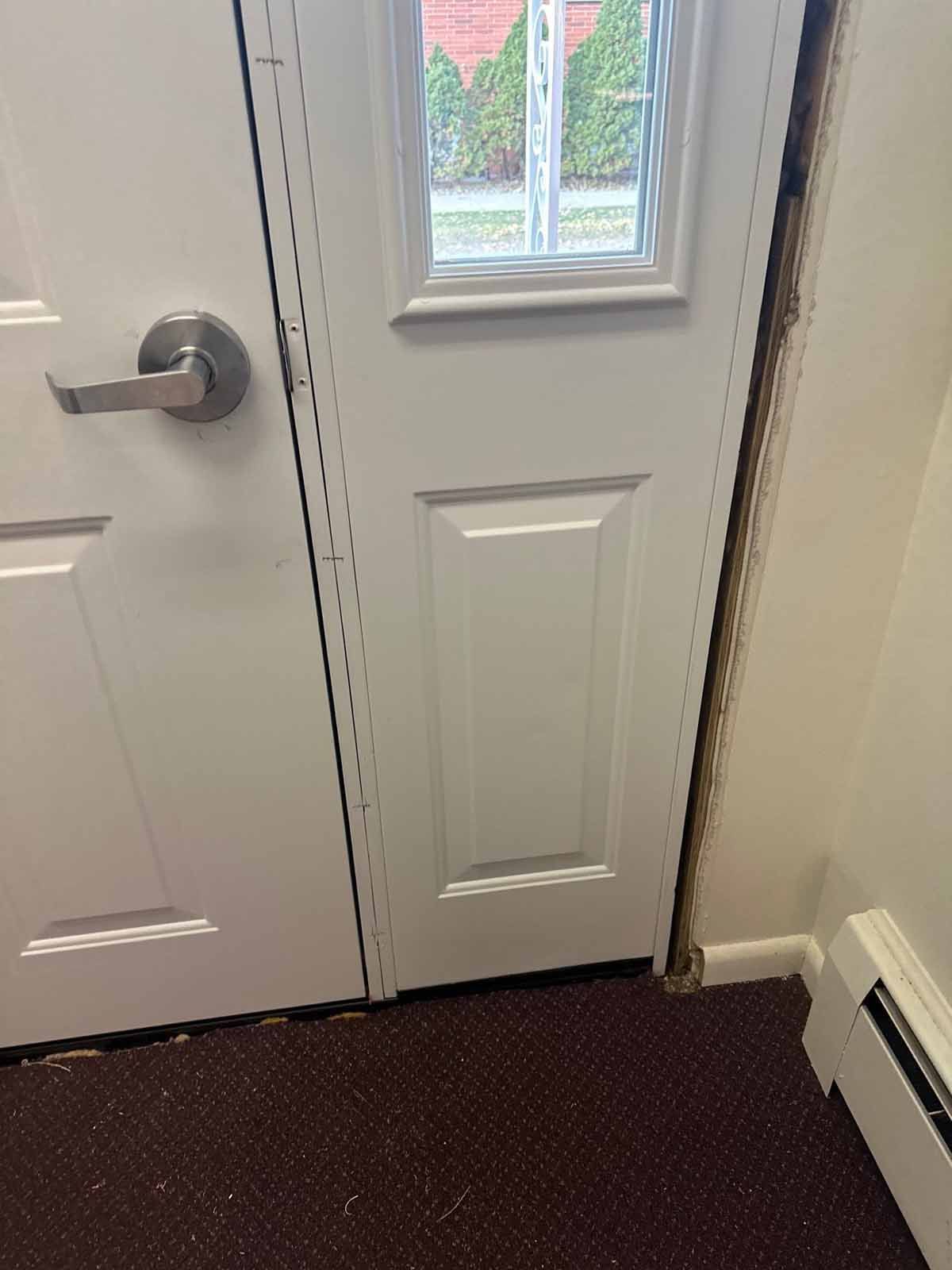 White door with a window and a silver handle, next to a beige wall.