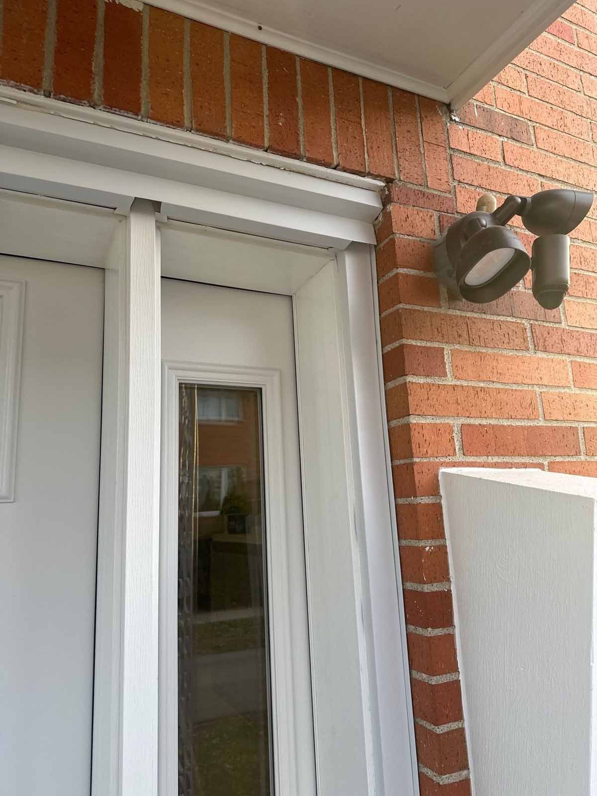 White door with glass panel, brick exterior wall, and outdoor light fixture.