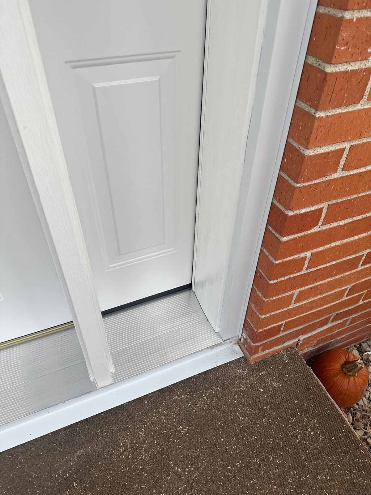 White door, door frame, and brick exterior with a small pumpkin on the ground.