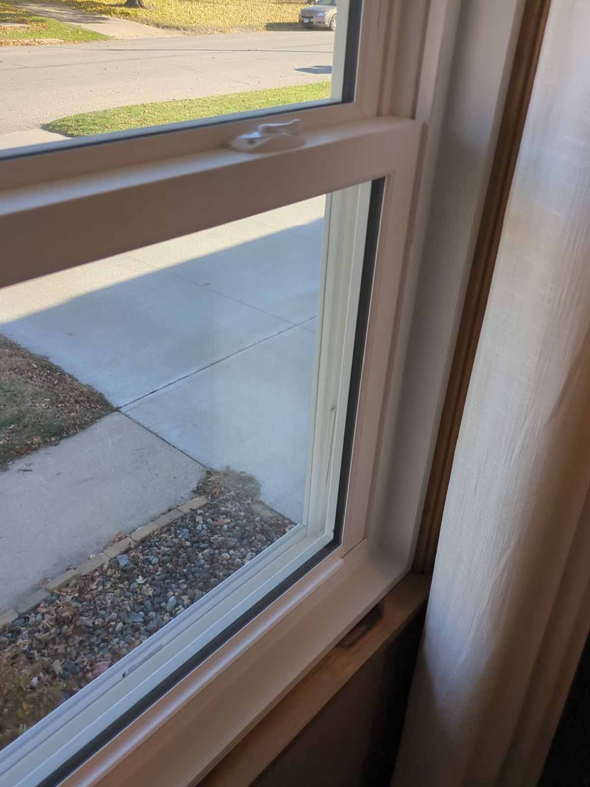 White framed window looking out onto a driveway and street.