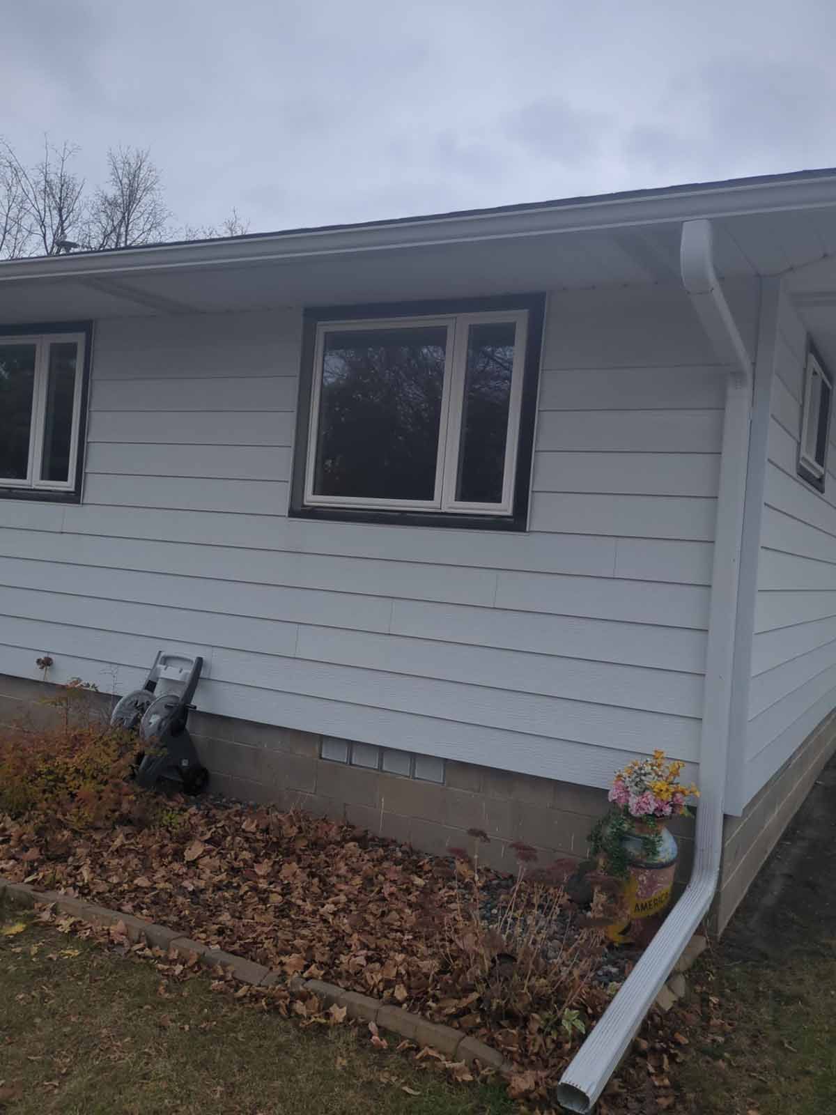 White house with white siding and dark brown window trim under an overcast sky.