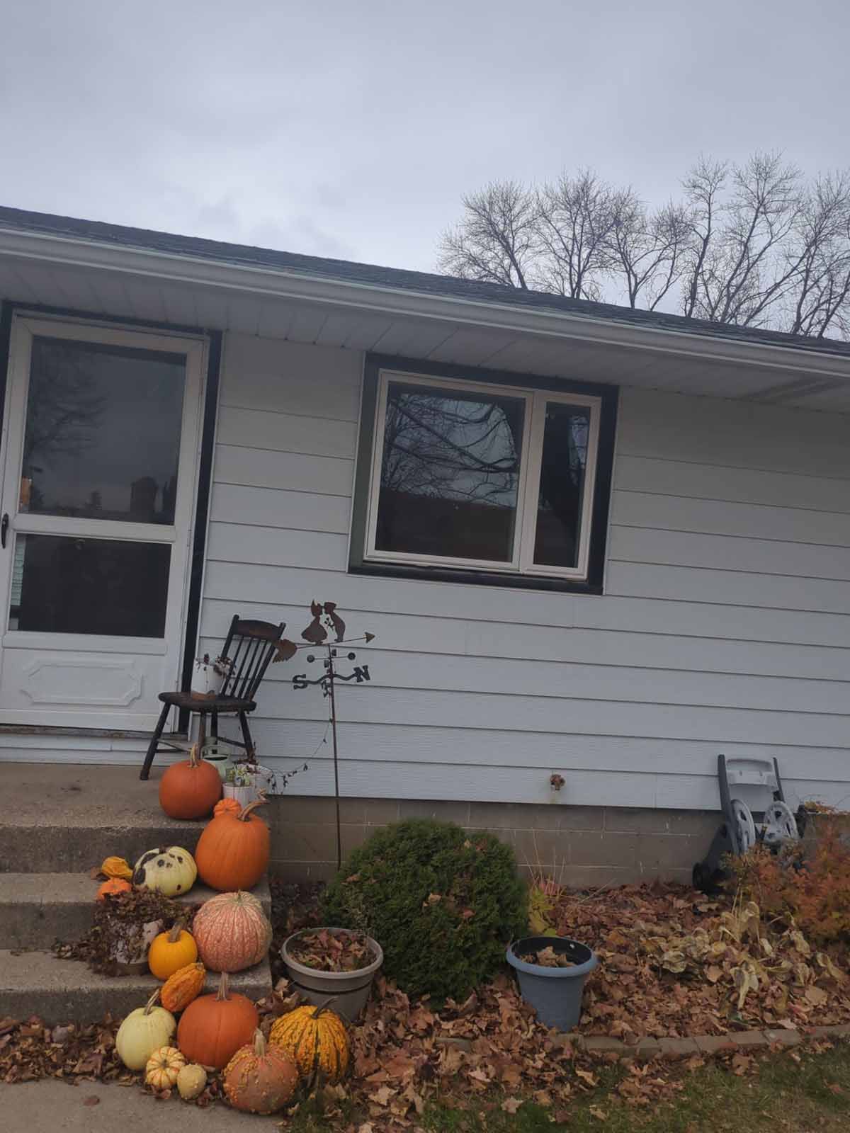 A house decorated for fall, with pumpkins on the porch.