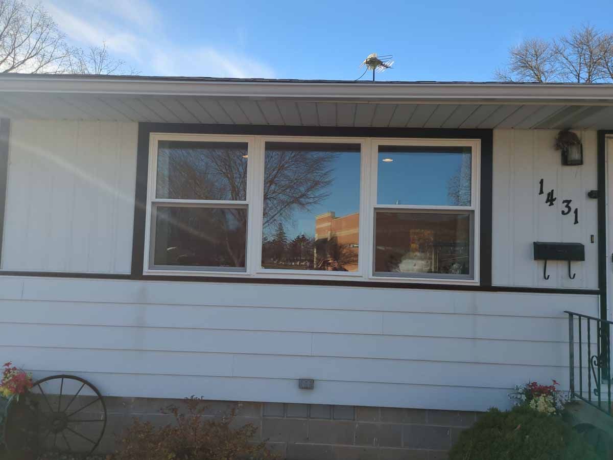 White house with a large window reflecting a building and a blue sky. Number 1431 on the right.