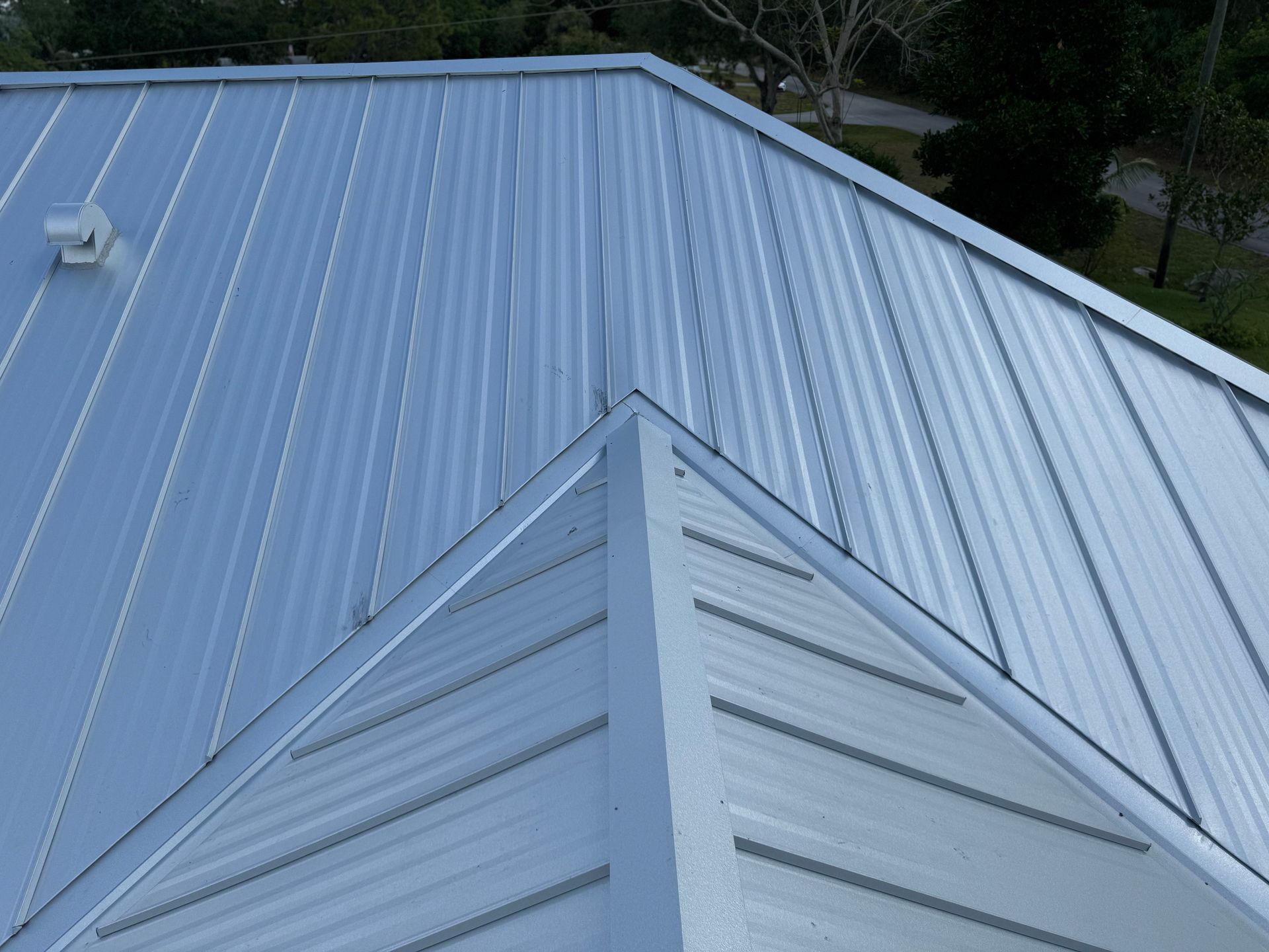 A metal roof with a white siding and a fan on it
