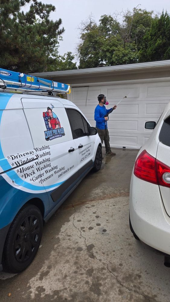 A man is cleaning a garage door next to a van.