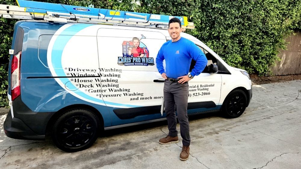 A man is standing in front of a van with a ladder on top of it.
