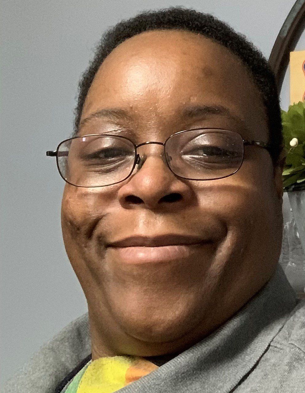 A woman wearing glasses and a tie is smiling for the camera.