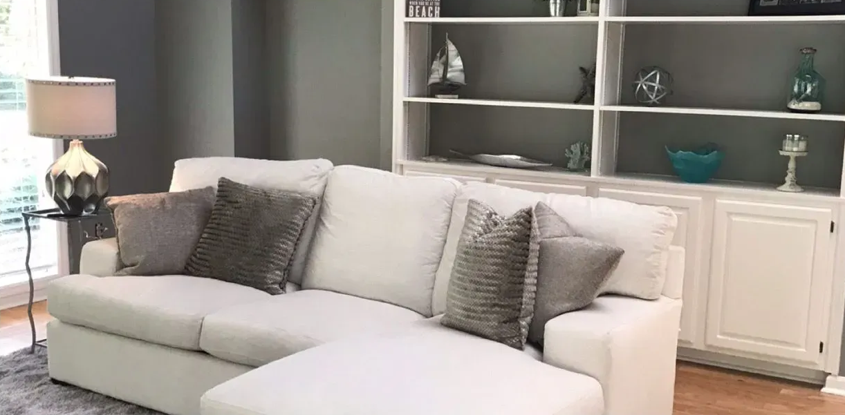 White sectional sofa in a living room with gray walls and built-in white shelving.