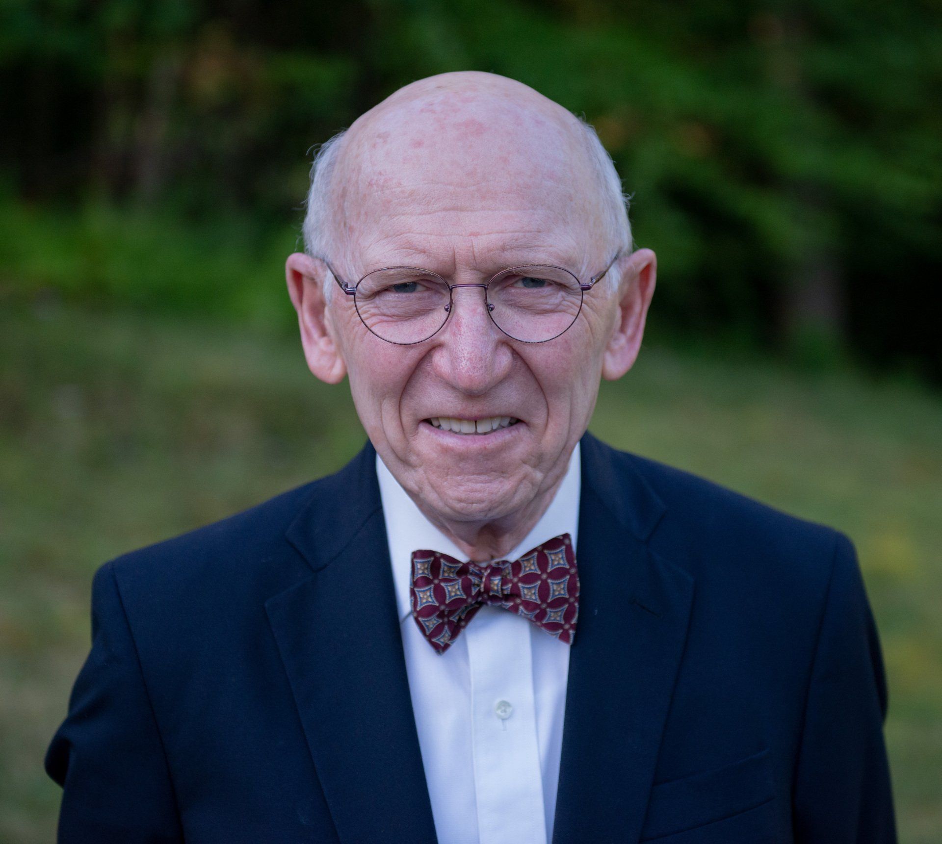 A man in a suit and bow tie is smiling for the camera.