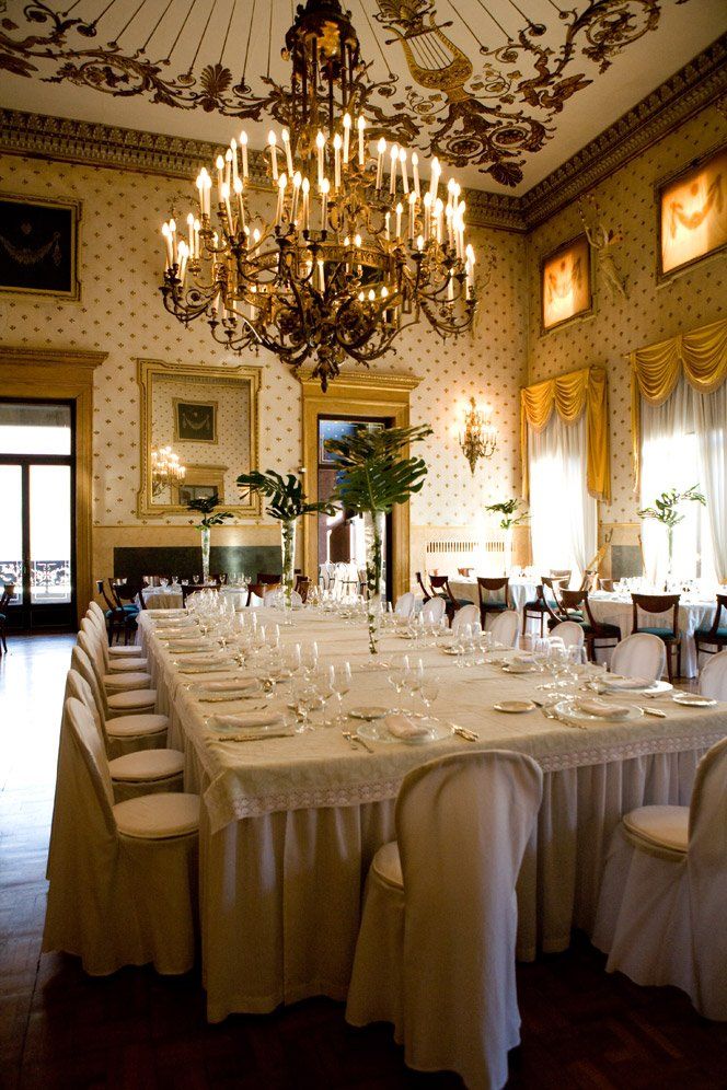 A long table in a room with a chandelier hanging from the ceiling