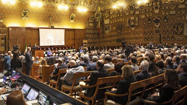 A large group of people are sitting in a large room watching a presentation.