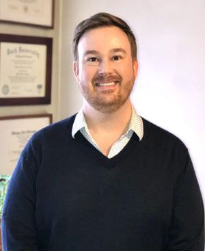 A woman wearing a black shirt and gold earrings smiles for the camera.