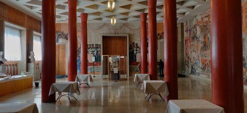 A large room with red columns and tables in it.