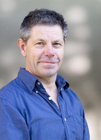 A man in a blue shirt is smiling for the camera.