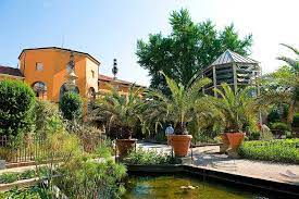 There is a pond in the middle of a garden with a building in the background.