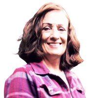 A woman in a plaid shirt is smiling for the camera.
