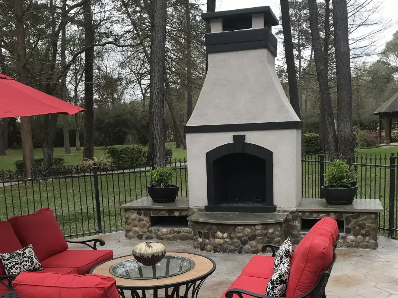 A patio with a fireplace and a red umbrella