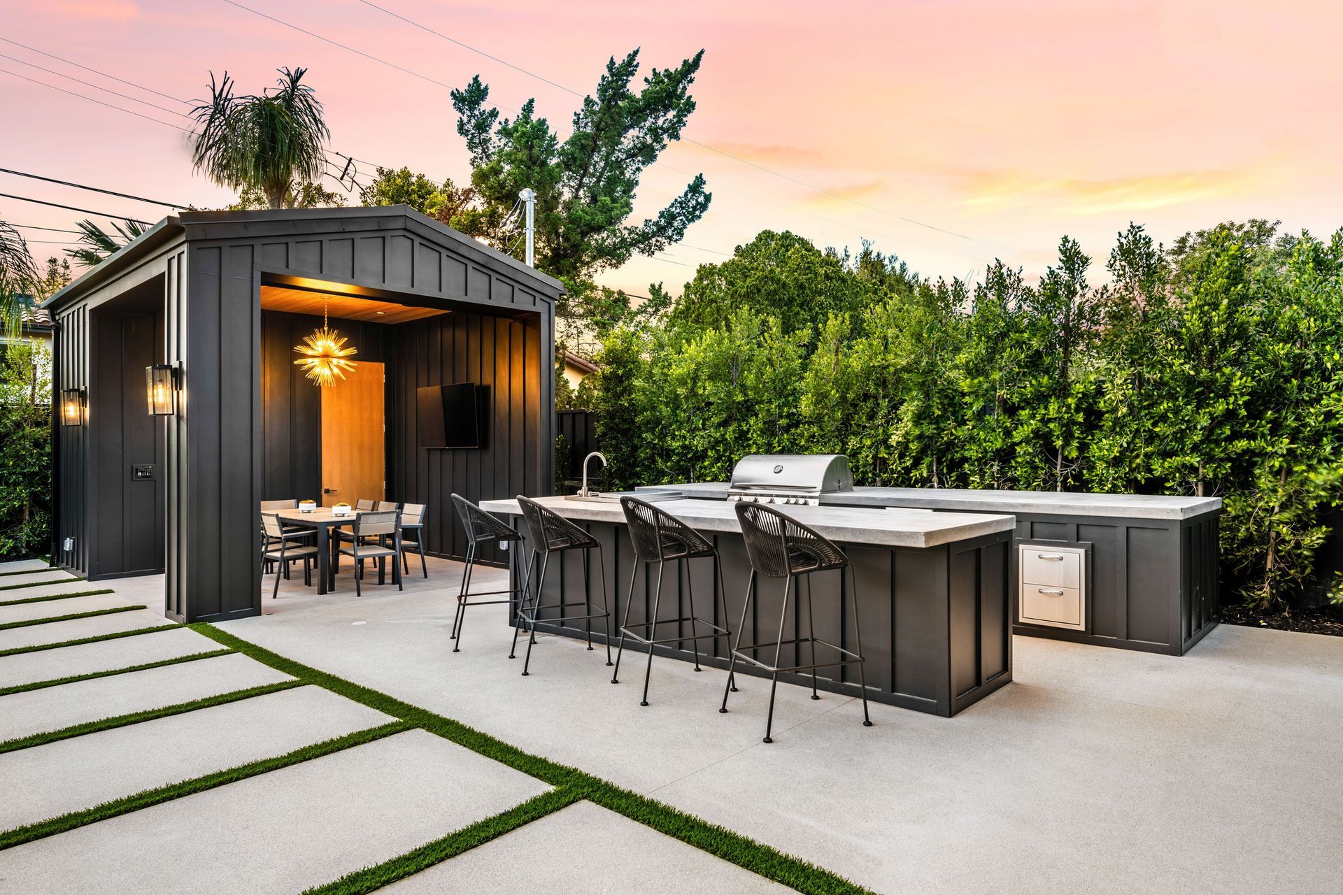 A large outdoor kitchen with a grill and stools