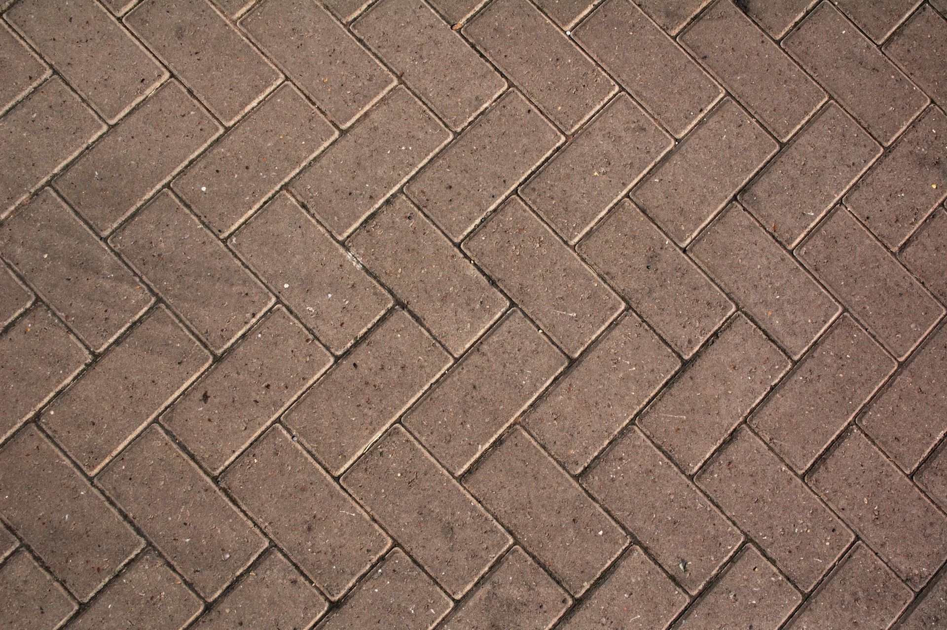 A close up of a brick pavement in a herringbone pattern.