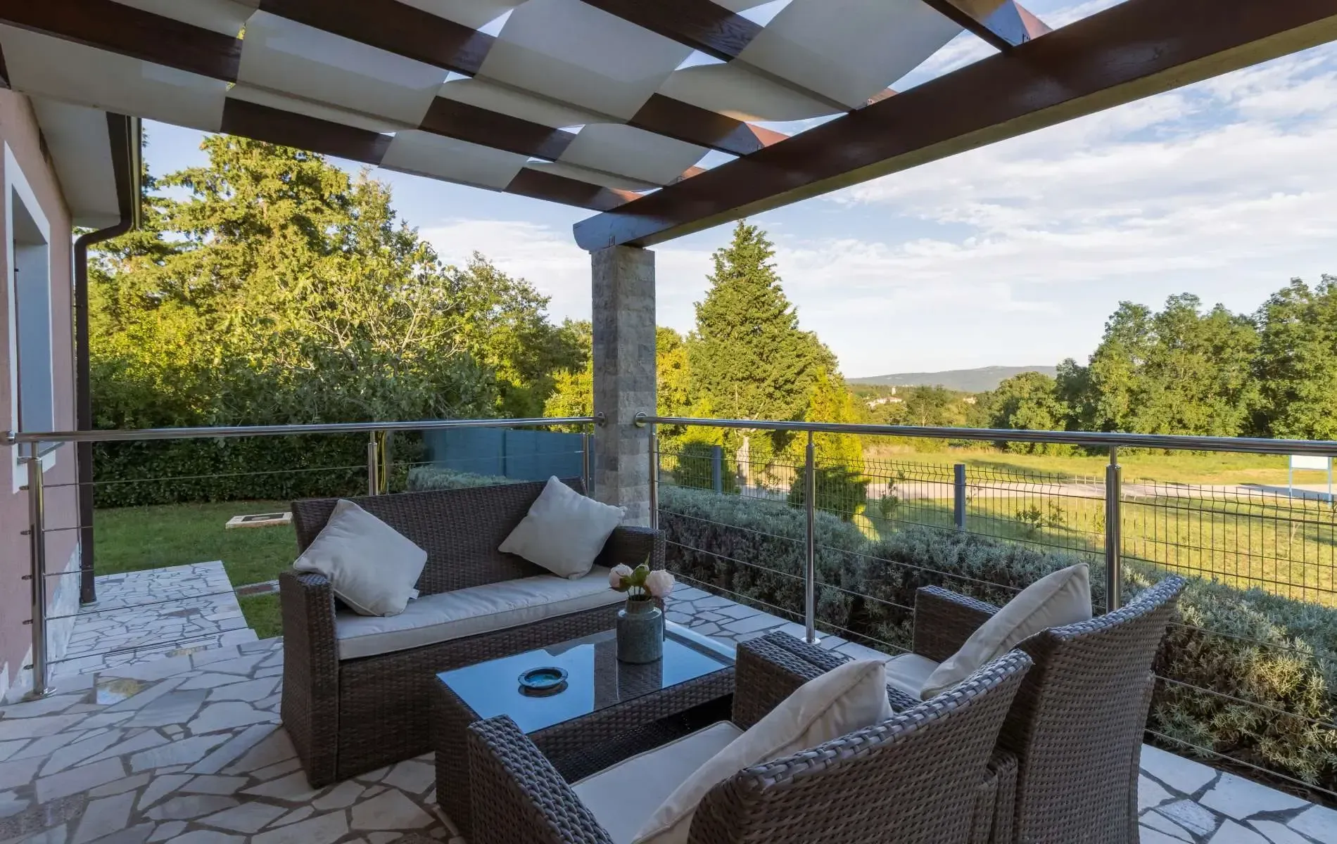 A patio with a couch , chairs and a table under a pergola.