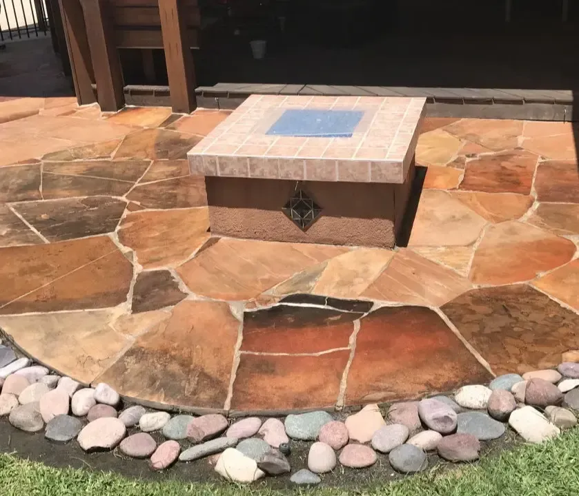 A fire pit is sitting on top of a stone patio surrounded by rocks.