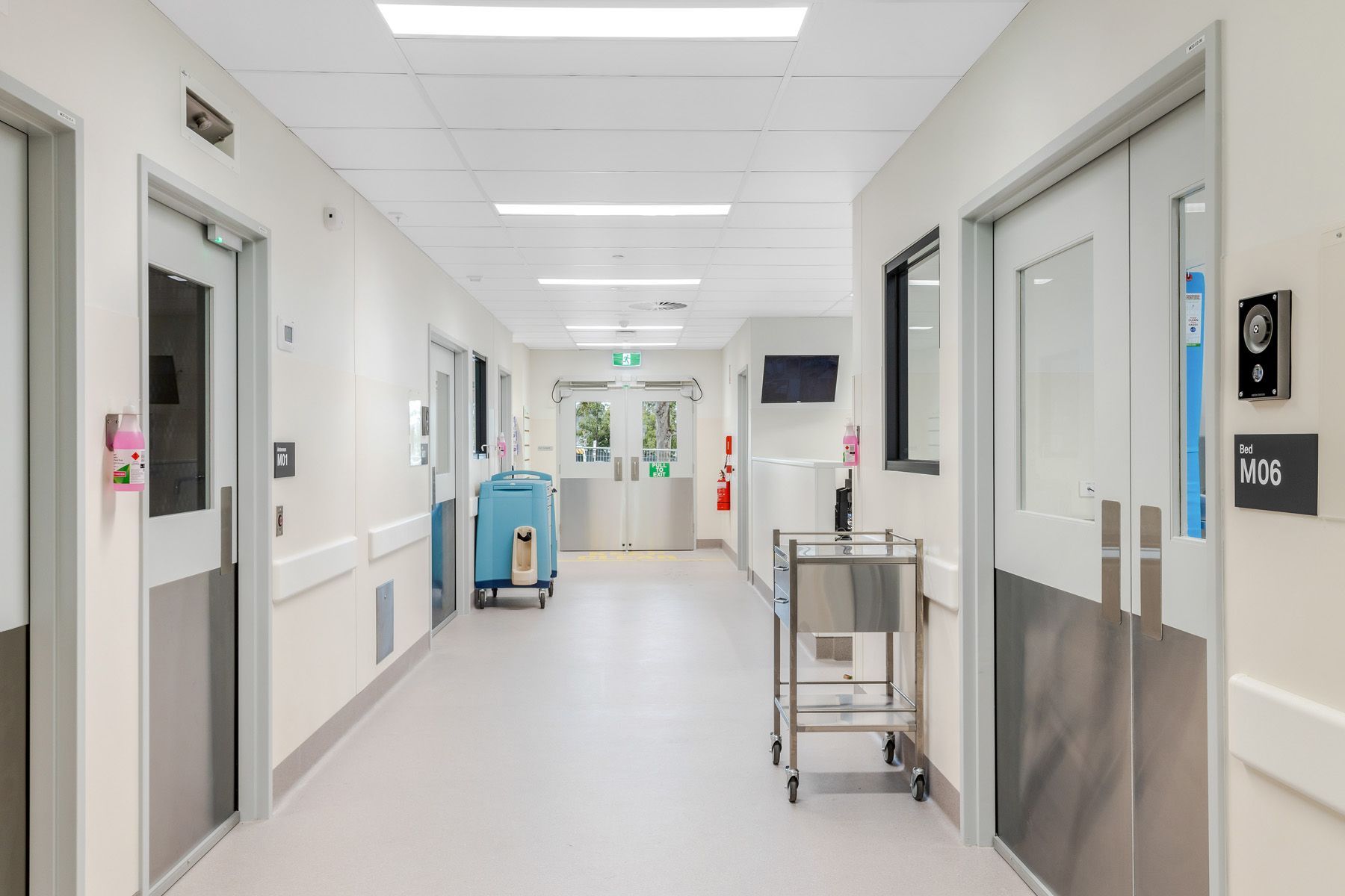 A hospital hallway with a cart in the middle of it.