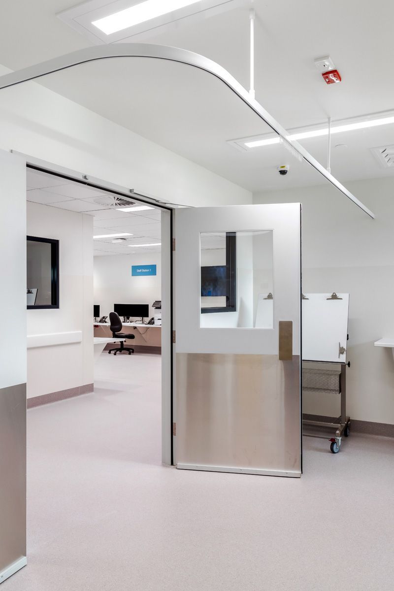 A stainless steel door is open in a hospital room.