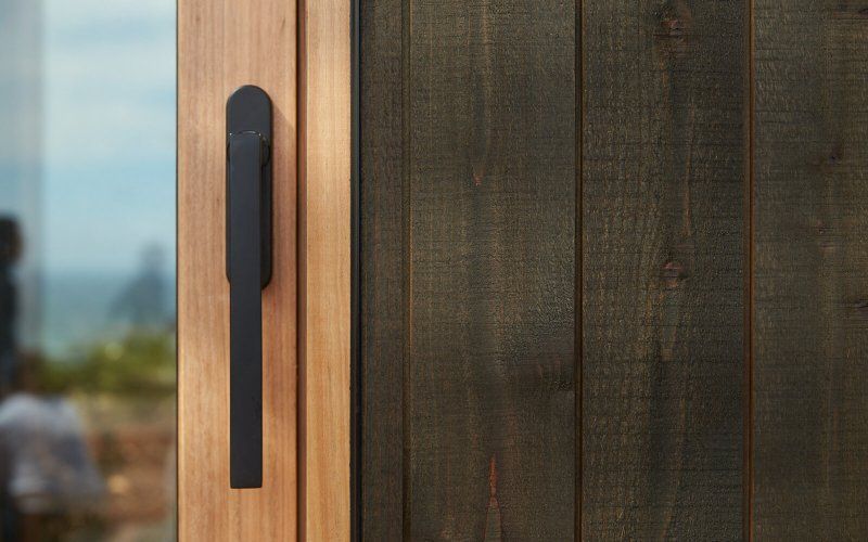 A close up of a wooden door with a black handle.
