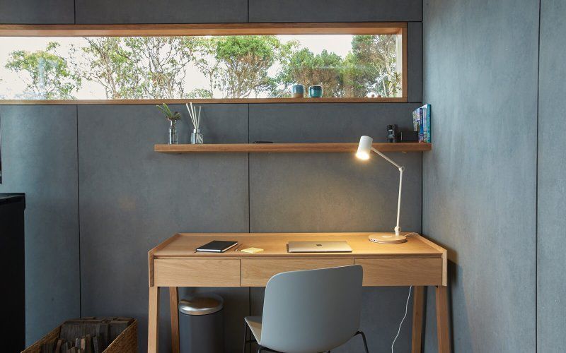 A desk with a lamp and a chair in a room with a window.