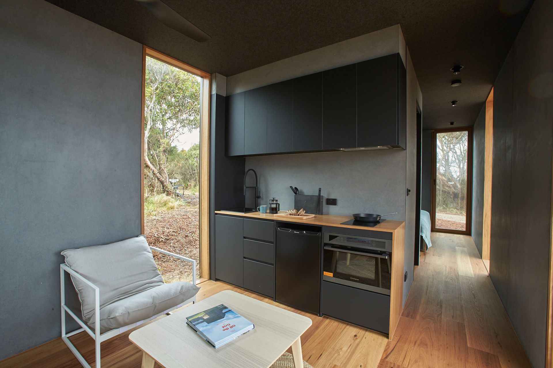 A living room with a chair , table , and kitchen.