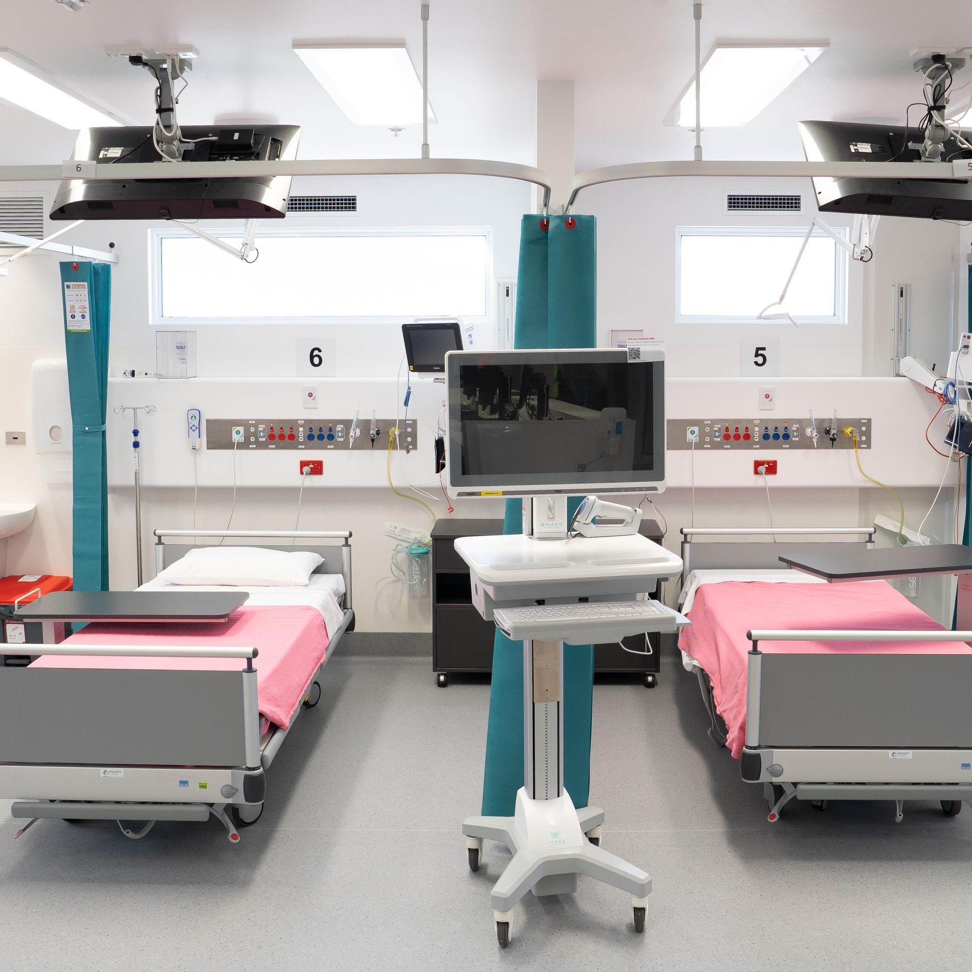 A hospital room with three beds and a monitor with the number 5 on it