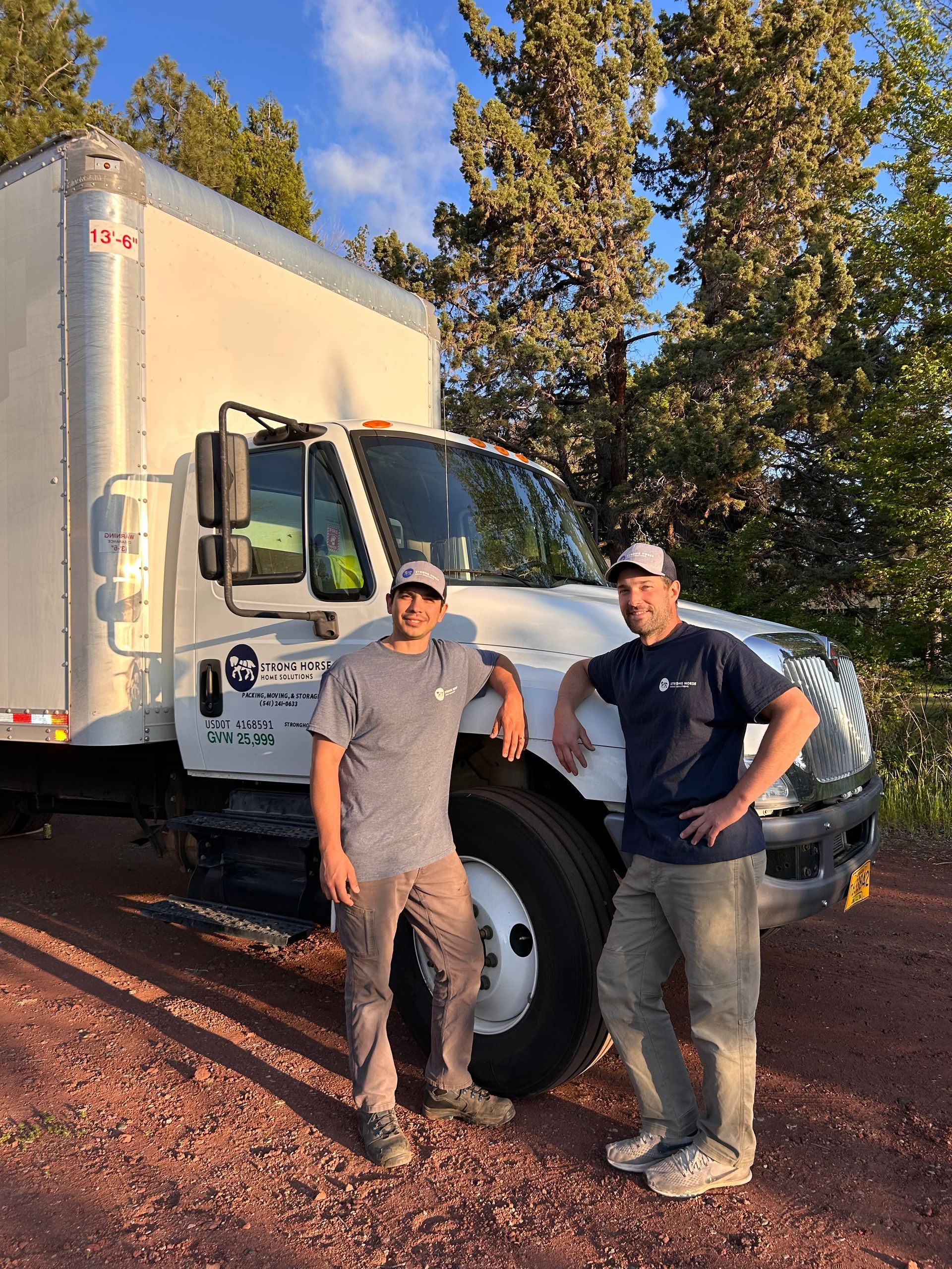 Two men are standing in front of a white truck.