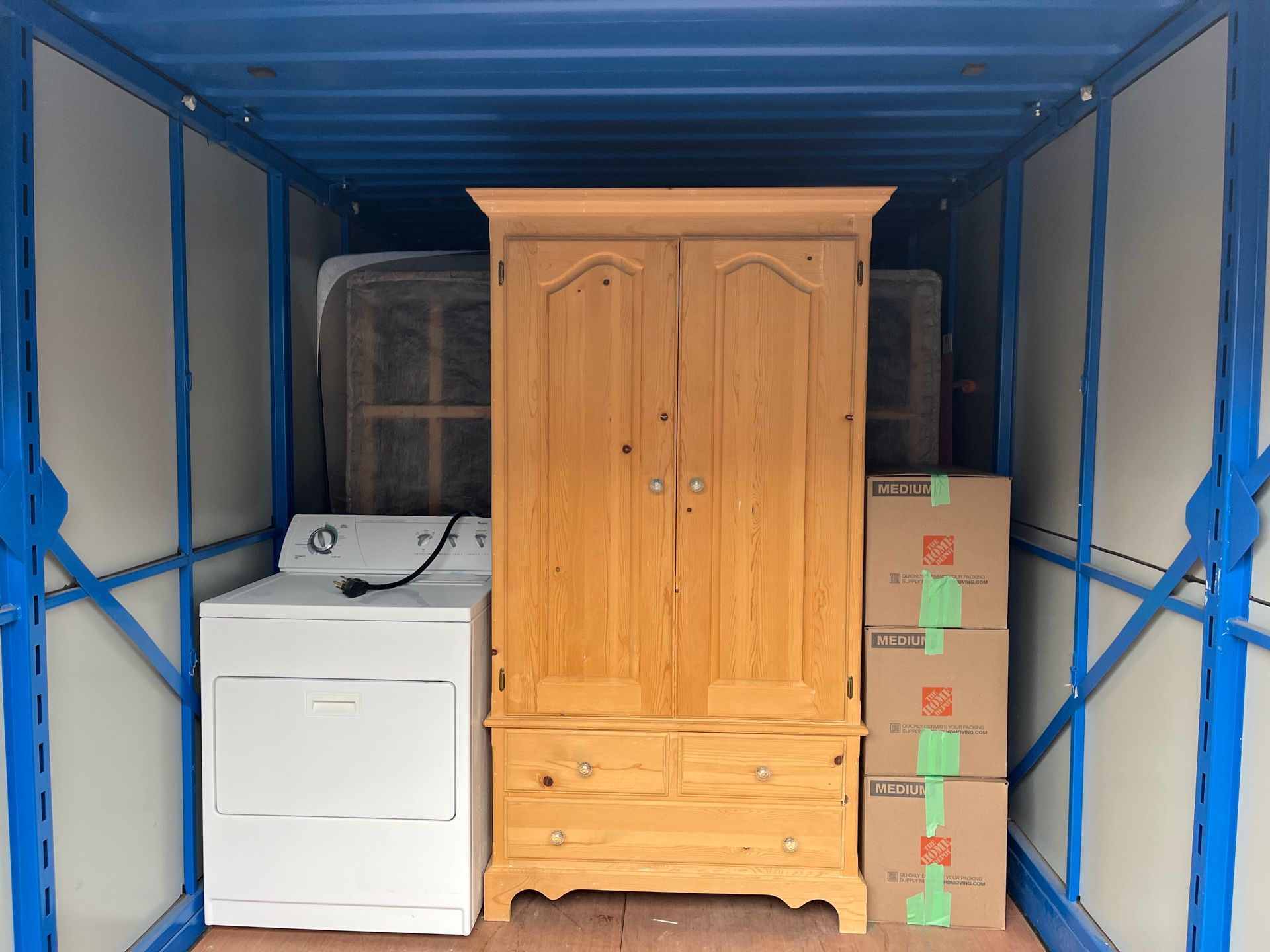 A washer and dryer are sitting inside of a blue container.