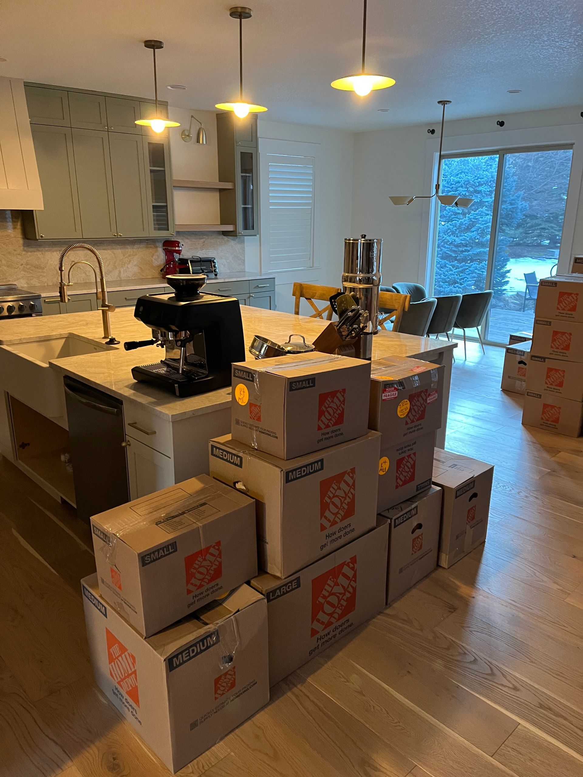 Kitchen island with stacked moving boxes; espresso machine and light fixtures visible.