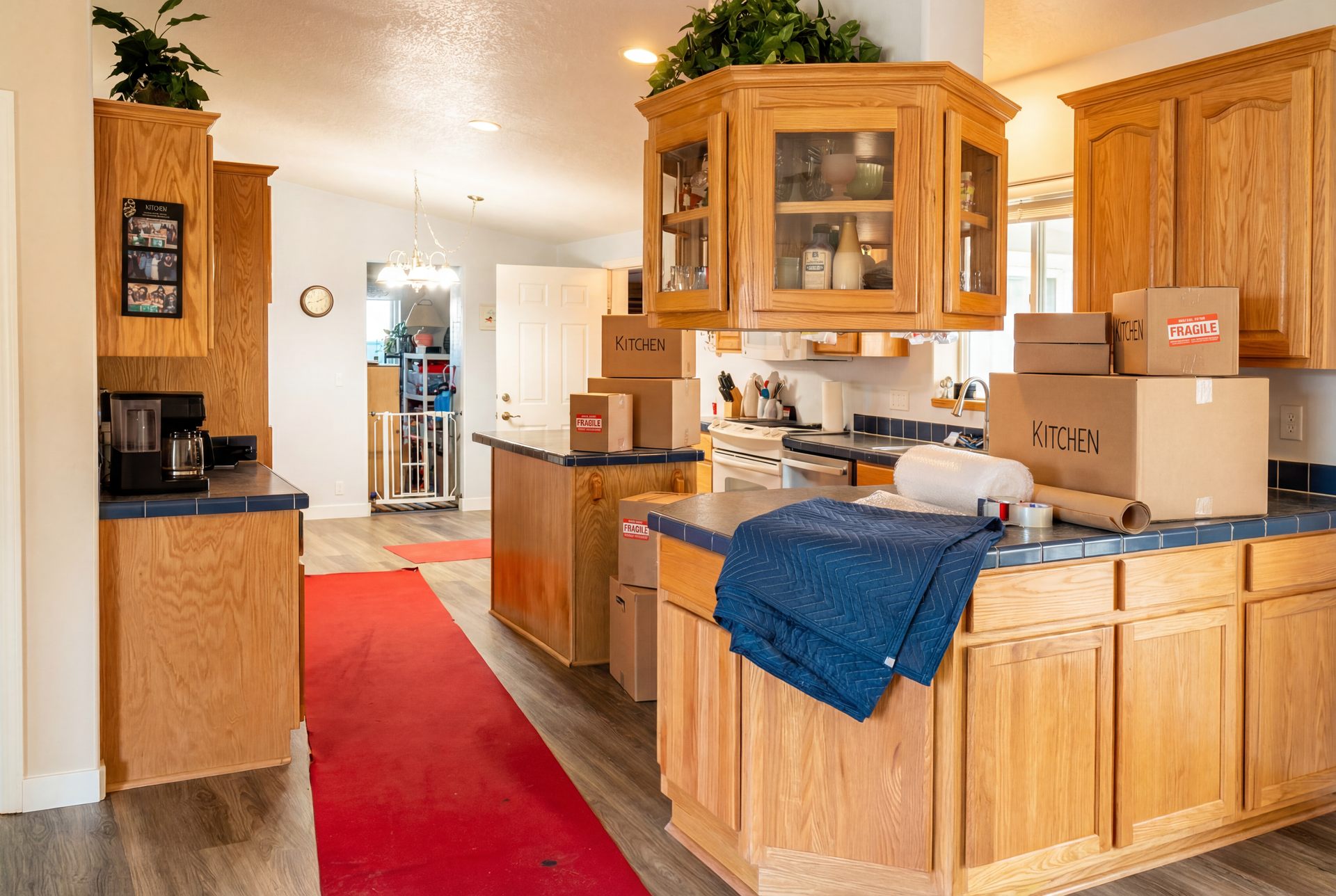 Kitchen with oak cabinets, moving boxes, and red runner rug.