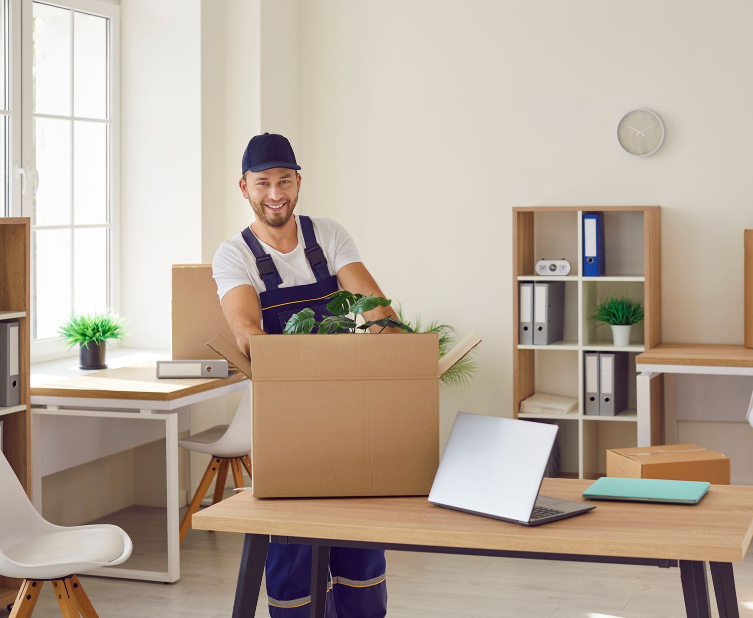 A man is holding a cardboard box in an office.