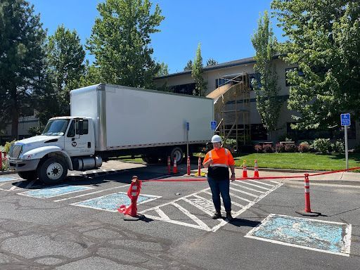 A man is standing in a field next to a truck holding a stack of pallets.