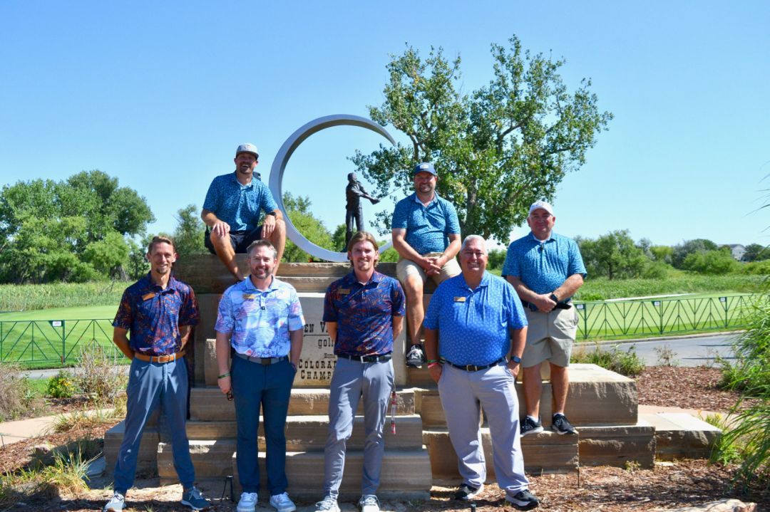 A group of people are posing for a picture in front of a statue.