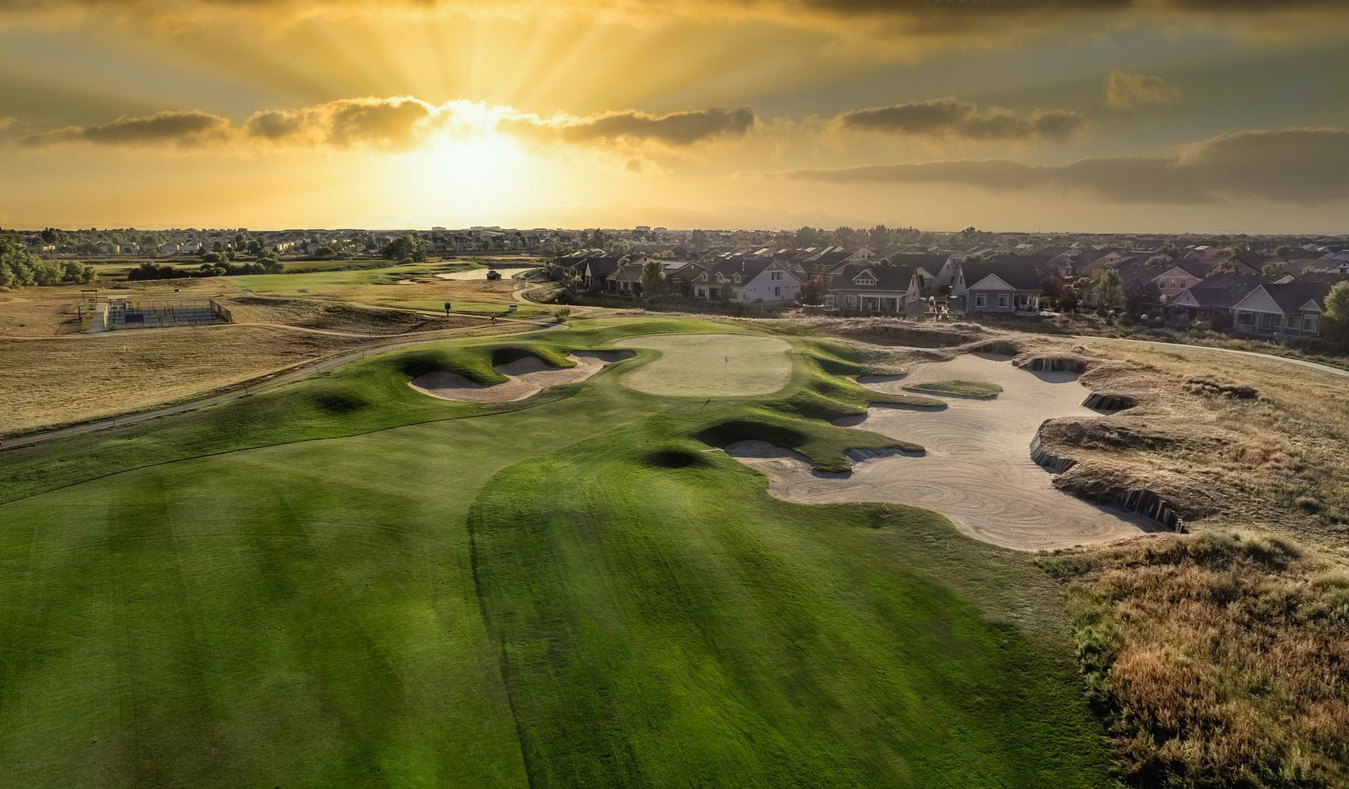An aerial view of a golf course with a city in the background
