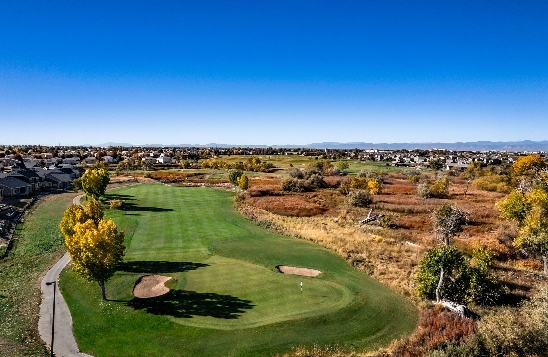 A golf course with a pond in the middle of it and mountains in the background.