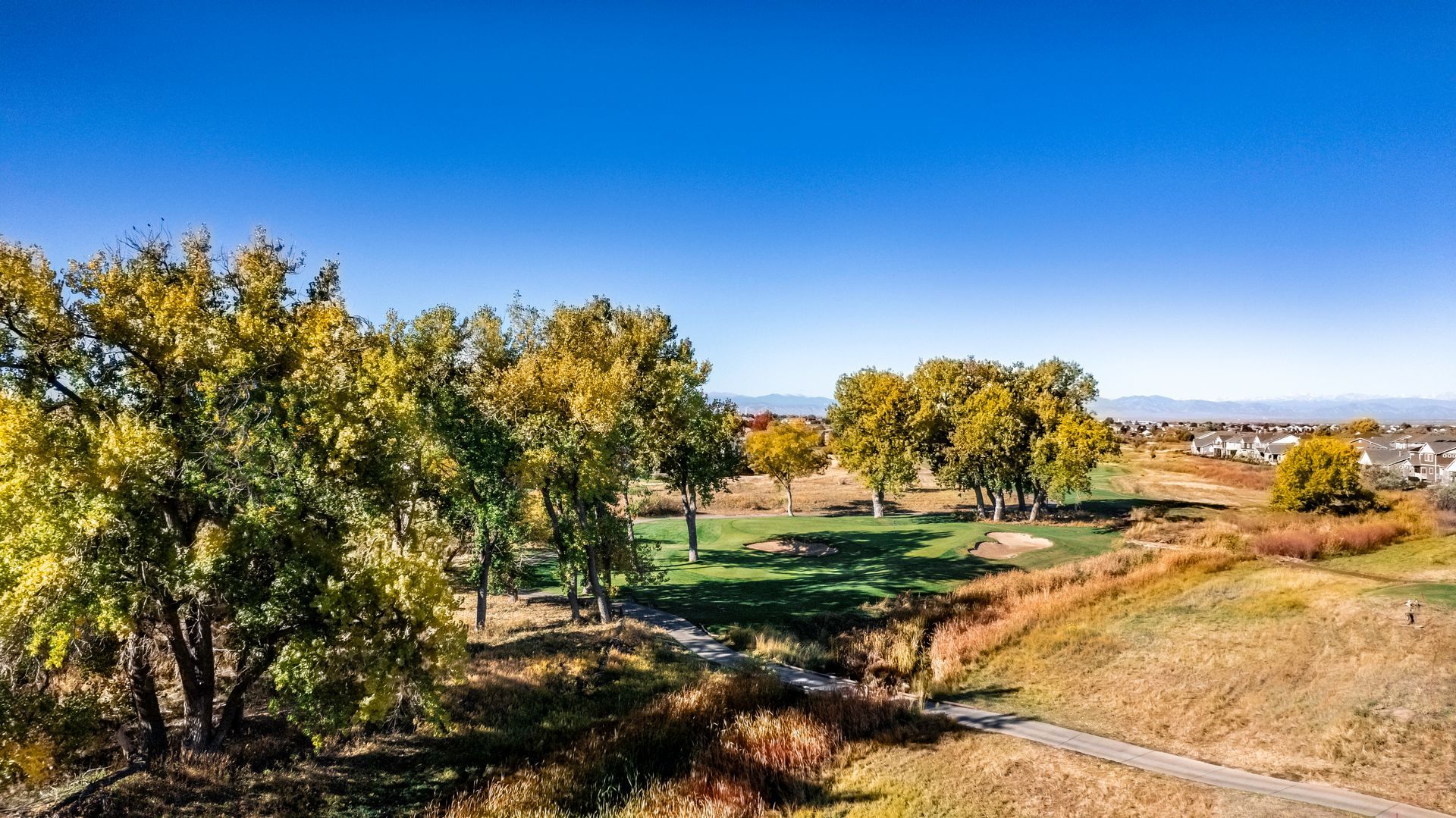 An aerial view of a golf course with houses in the background
