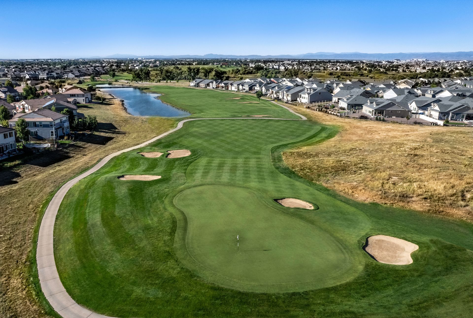 An aerial view of a golf course with a city in the background
