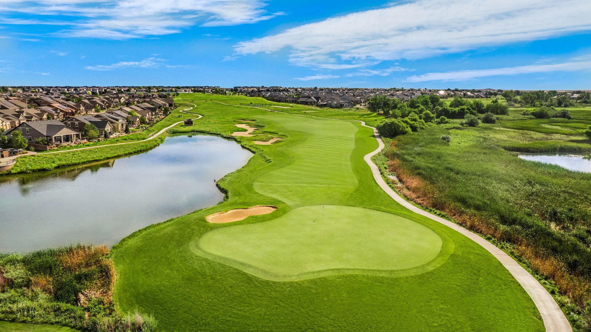 An aerial view of a golf course with a city in the background