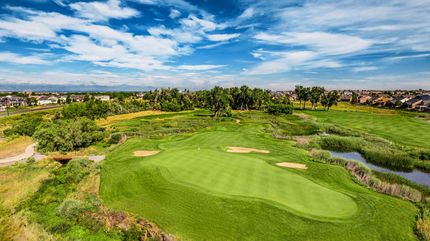 An aerial view of a golf course with a pond in the middle of it.