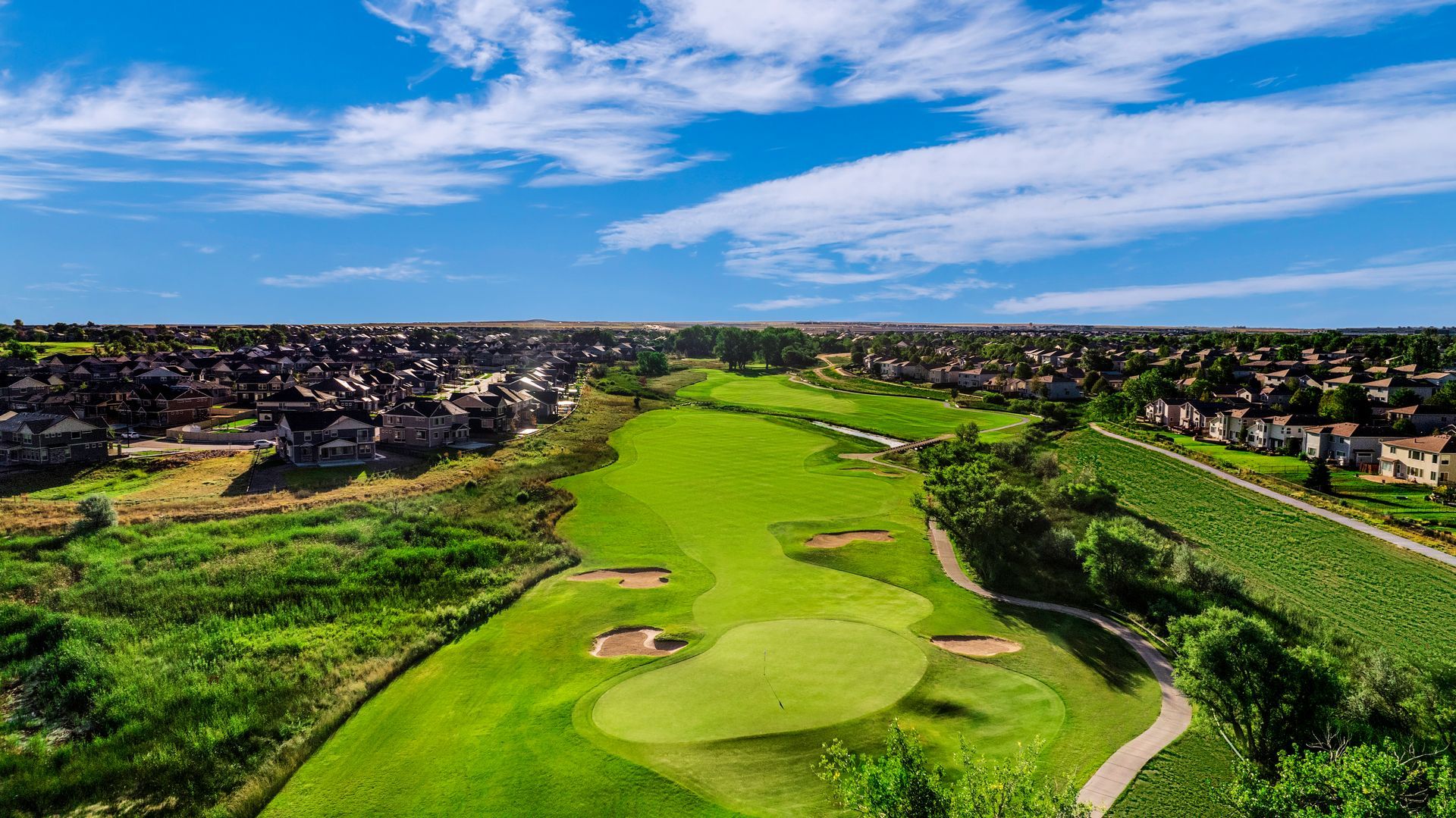 A large house with a porch is sitting on top of a lush green field.