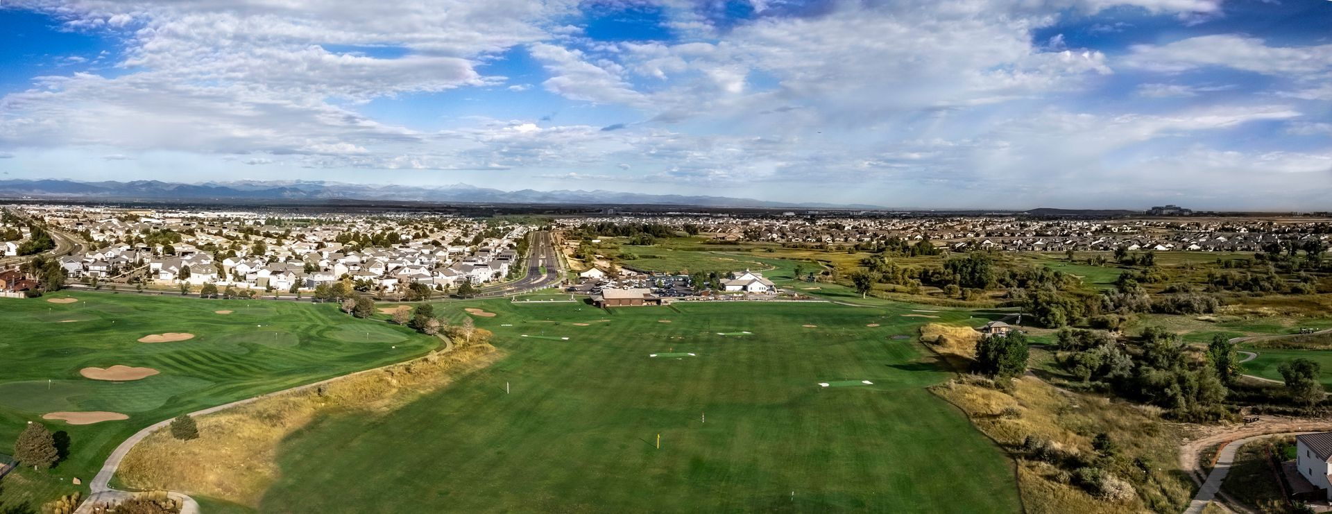 An aerial view of a golf course with a city in the background