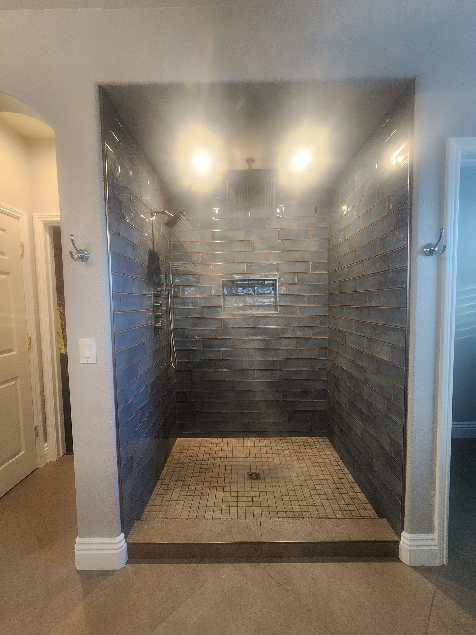 A shower with marble tiles and a bench in it.