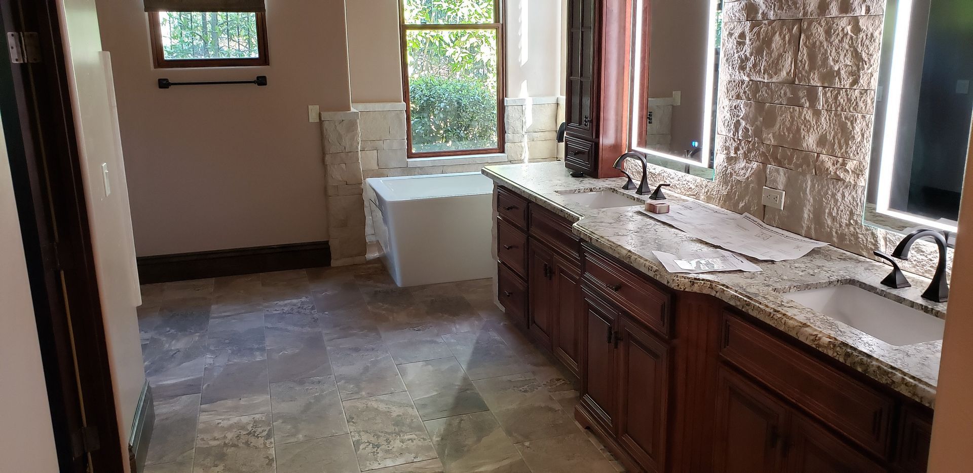 A bathroom with two sinks , a tub and a mirror.