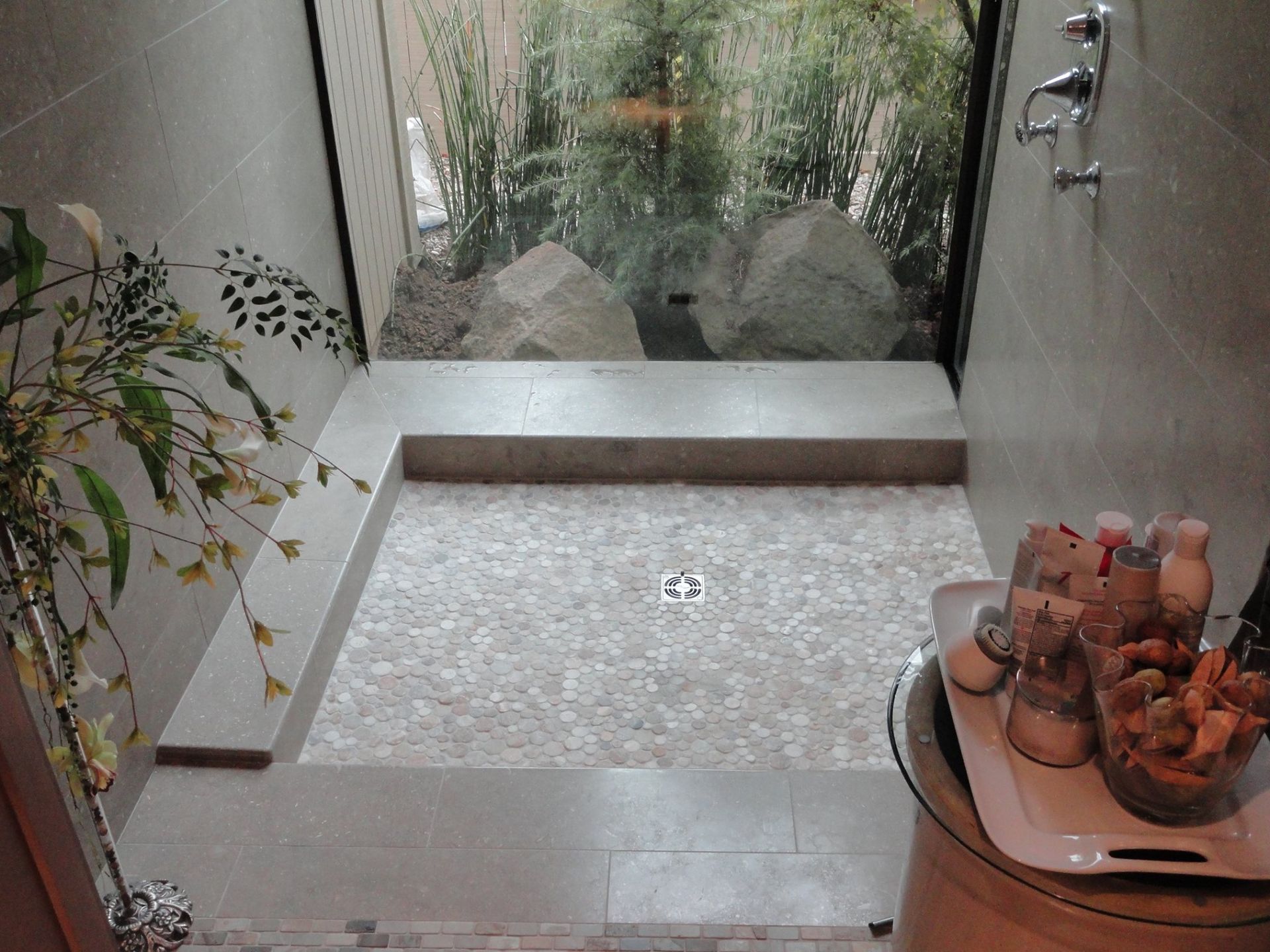 A bathroom with a walk in shower and a view of a garden