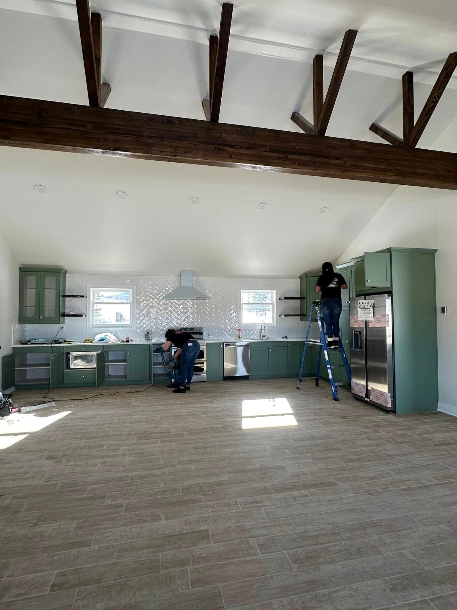A person wearing green gloves is cleaning a table with a cloth.